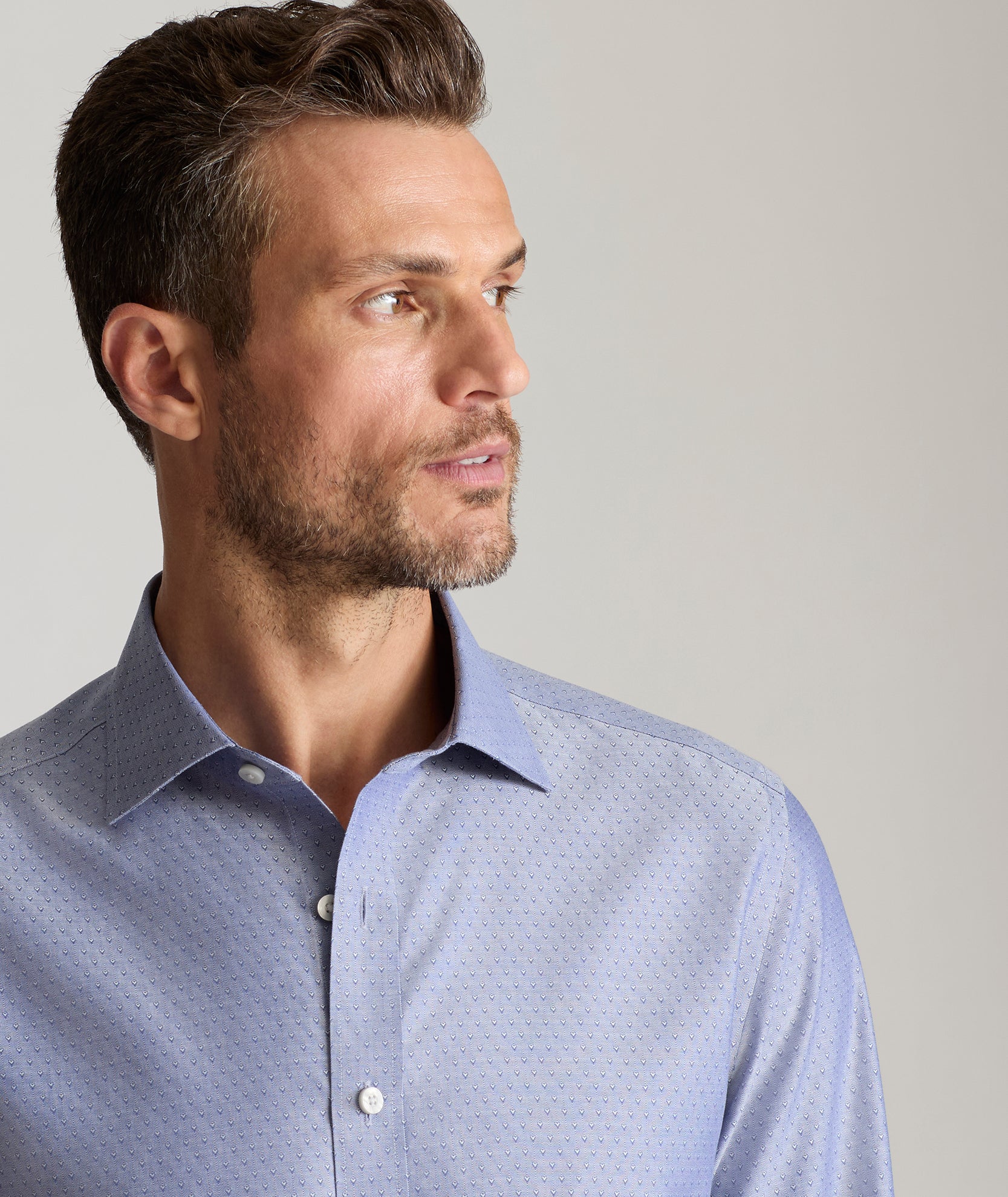 Model is wearing UNTUCKit Oliver wrinkle free shirt in gray blue print. 